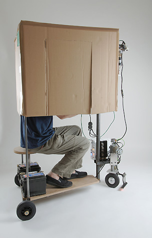 Piet.sO et Peter Keene installation performance à propos de confinement et de redécouverte d'un espace restreint par l'aide d'un véhicule monoplace surmonté d'un carton et équipé d'un périscope.