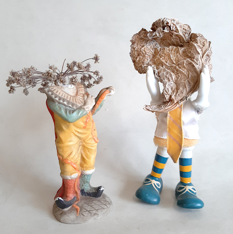 Piet.sO,clowns installation, tentative de protection contre le coronavirus. 2 clowns tentent la feuille de chou ou le rempalcement de la tête. assemblage collage sur statuette revisitée, art contemporain à propos du covid