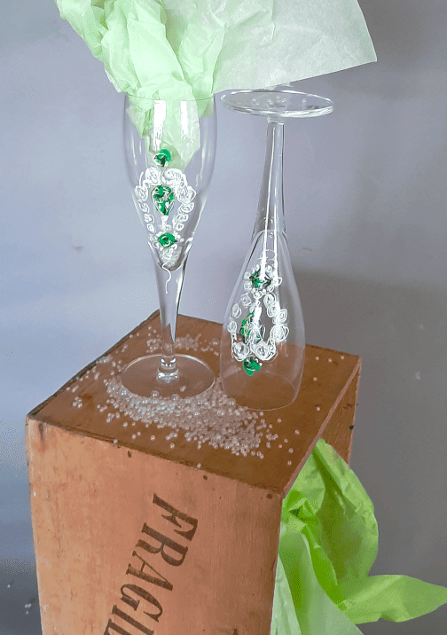 installation avec dessin des boucles d'oreilles de la parure d'émeraudes sur verre à pied.