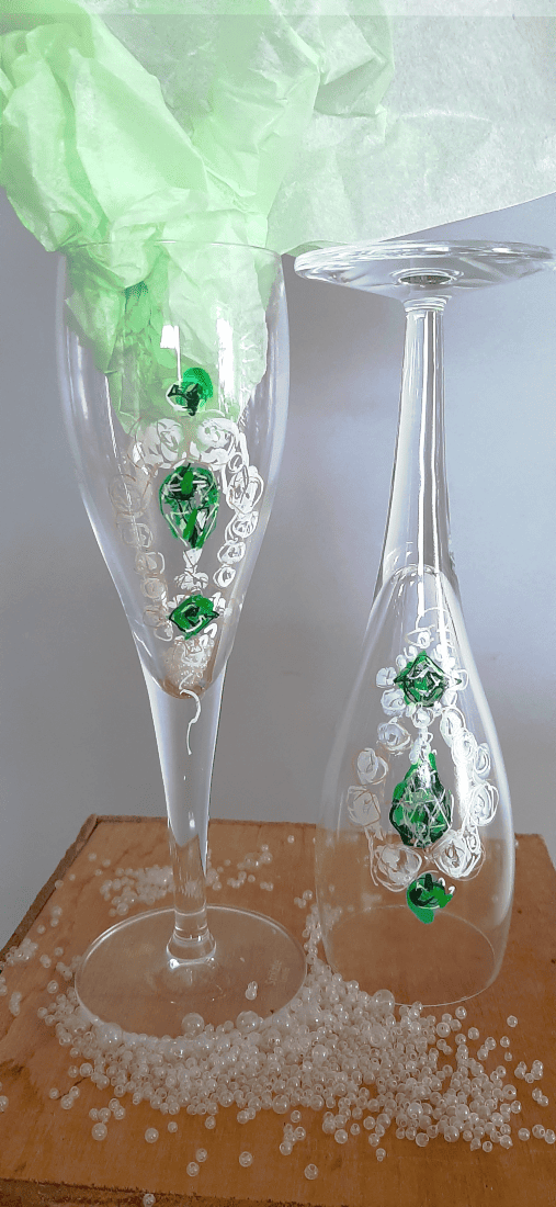 Détail du dessin des boucles d'oreilles de la parure d'émeraude sur verres à champagne., joyau du en référence au casse du siècle au Louvre en 2025.